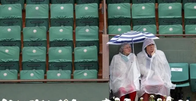 photo les spectateurs se protègent de la pluie en attendant, peut-être, le début des matches aujourd'hui. &copy; reuters
