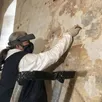 photo  véronique legoux est conservatrice restauratrice de peintures murales. perchée sur un escabeau, elle élimine avec un scalpel des éléments de badigeon. 