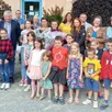 photo  emmanuelle chrétien (au milieu), pour un au-revoir, derrière son bouquet de fleurs. elle est entourée de sa fille, des élus, parents et enfants de la commune. 