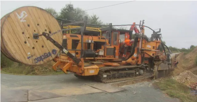 photo  les engins sont impressionnants : celui-ci tranche le sol, déroule le câble, dépose le sable et le filet protecteur. 
