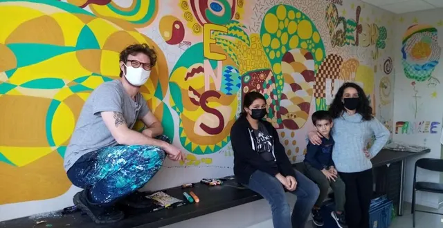 photo  la fresque, signée des ados et des enfants avec l’artiste joe popi, embellit la salle de rencontre et de partage entre les familles. 