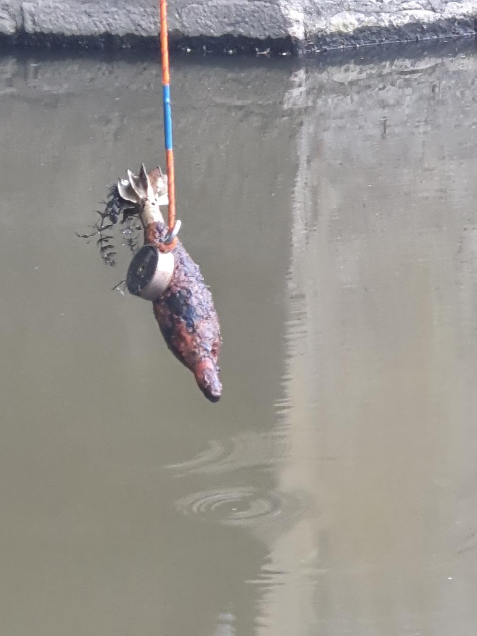 Un pêcheur à l'aimant sort un obus de la rivière 