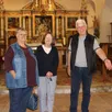 photo  josiane brahim, suzanne wigmore et jean-pierre bansard, membres de l’association de sauvegarde du patrimoine de réveillon, devant le retable de l’église. on aperçoit un strapontin. 