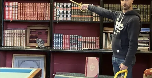 photo  pierre-emmannuel lecot devant la bibliothèque retrouvée, le sabre du général rey à la main.  &copy;  pierre-emmannuel lecot 