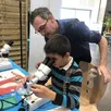 photo aurélien et son fils gaëtan utilisent le microscope pour voir les détails d’une plume d’oiseau.