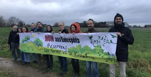 photo  le collectif devant le terrain où devrait être construit l’entrepôt de 3,5 hectares à trangé.  &copy;  photo le maine libre 