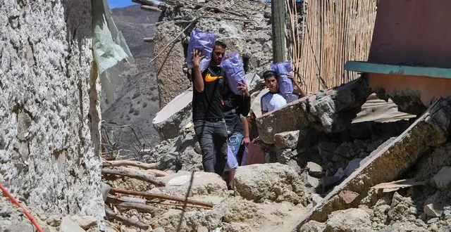 photo  des hommes transportant des provisions, lundi 11 septembre 2023, dans un village marocain détruit par le tremblement de terre survenu dans le haut-atlas.  &copy;  fethi belaid / afp 