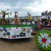photo  le char de la commune arrive en tête du défilé, suivi de nombreux chars décorés suivis de villageois costumés. 