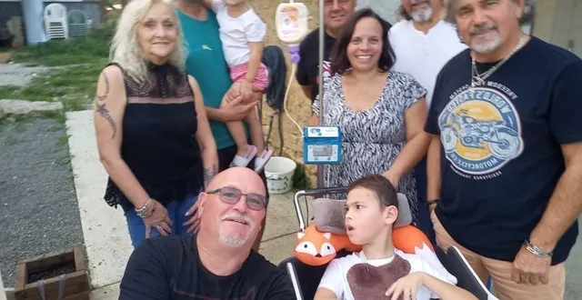 photo  elyo entouré par amélie sa maman, colyne sa petite sœur dans les bras d’alexandre son papa, et quelques motards de l’association.  &copy;  le maine libre 