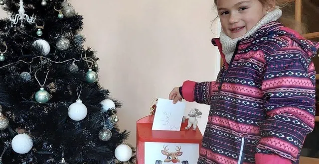 photo  anna, 6 ans, dépose sa lettre au père noël dans la boîte prévue pour, dans le hall de la mairie.  &copy;  le maine libre 