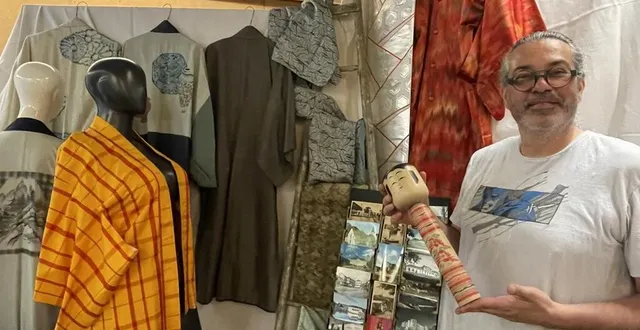 photo  laurent yodel motillon tient une poupée kokeshi de grande taille, en bois. à sa droite, une veste haori rouge et jaune, des kimonos et des ceintures (obi).  &copy;  le maine libre 