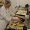photo maéva, l’une des employées, réalise l’étape du fourrage au praliné du manceau, le nouveau gâteau lancé par maison drans.