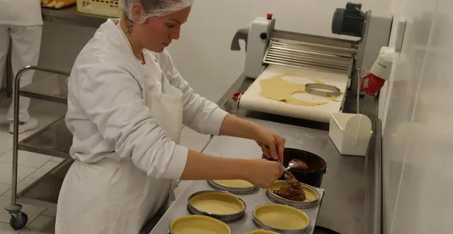 photo  maéva, l’une des employées, réalise l’étape du fourrage au praliné du manceau, le nouveau gâteau lancé par maison drans.  &copy;  ouest-france 