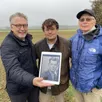 photo john haller (à gauche) et son frère bill, avec une photo de leur père, dans le champ à urou-et-crennes où ce dernier a été fait prisonnier le 19 août 1944. les fils de l’ancien gi sont accompagnés par tristan rondeau, historien et spécialiste des combats de la poche chambois-falaise.