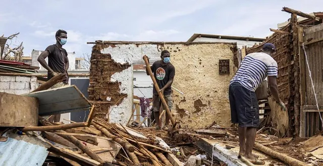 photo  des hommes en train de nettoyer au milieu des débris, dans la ville mahoraise de mamoudzou, le 22 décembre, après le passage du cyclone chido.  &copy;  patrick meinhardt/afp 
