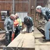 photo le bois du plancher de l’autorail de dion bouton débité par rémy sous les encouragements des bénévoles.