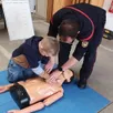 photo  un pompier volontaire montrant les gestes de premiers secours a un jeune visiteur. 