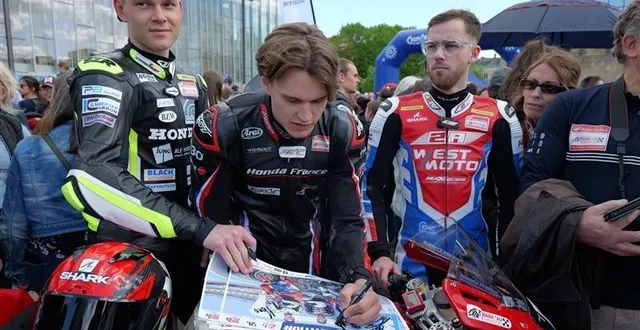 photo  les pilotes des 24 heures motos se prêtent, avec le sourire, à la séance des autographes sur les posters des écuries.  &copy;  enzo maubert 