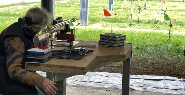photo  le rimfire se pratique assis. les cibles sont à 50 m de la carabine et entre les deux, des girouettes qui aident la tireuse de la photo à 