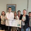 photo  théo et iliana remettent un chèque solidaire de 1 000 € entourés des bénévoles de l’association. 