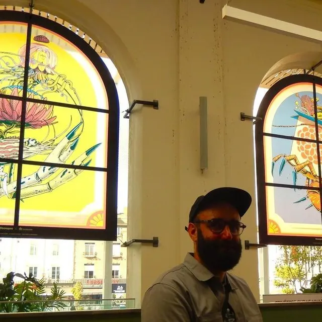 photo stom500 devant ses créations de vitrophanie créée à la gare du mans pour le festival plein champ 2025.  ©  ouest-france