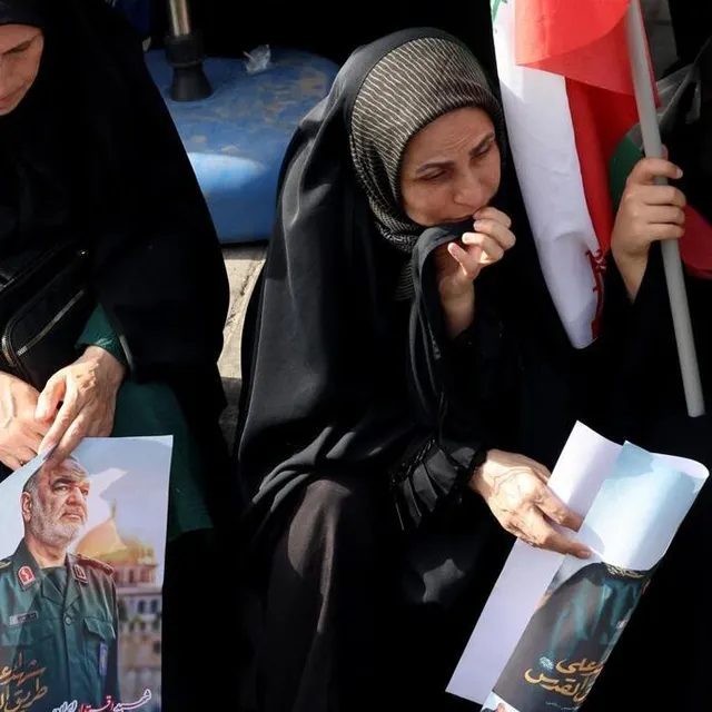 photo des femmes en deuil tenant des affiches du commandant du corps des gardiens de la révolution islamique (irgc), hossein salami, sont assises sur le bord de la chaussée et regardent les funérailles du commandant des gardiens de la révolution iranienne pendant leur procession funéraire sur la place enghelab.  ©  atta kenare / afp