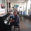photo armel de la bouillerie joue du piano et chante en gare du mans comme un vrai concert improvisé, pour le bonheur de certains voyageurs.