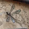 photo une libellule sculptée par cédric doret et agrémentée de verre par verr i kiti, orne le mur d’une maison d’asnières-sur-vègre ; cette sculpture fait partie du bestiaire de la vègre, objet d’une visite guidée dans le cadre des dimanches de caractère.