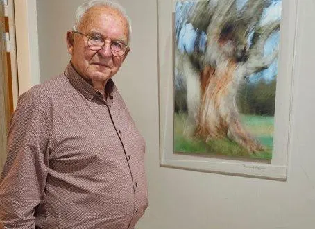 photo  bernard reignier devant une photographie d’un arbre, qui semble vouloir s’arracher du sol.  &copy;  le maine libre 