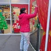 photo  ici, flora monti travaillant sur la vitrine du super u mareil-en-champagne, parée pour les fêtes de fin d’année. 