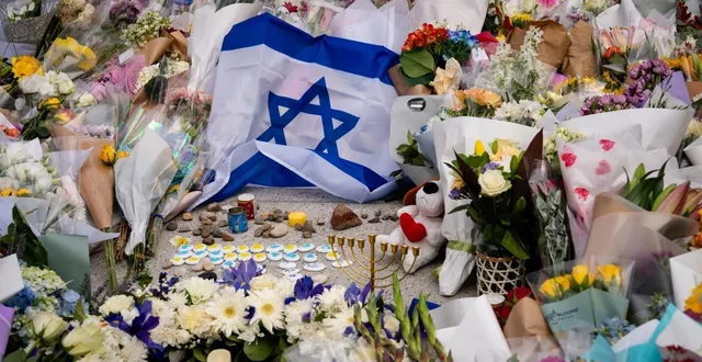 photo  un drapeau israélien et des fleurs ont été déposés devant le bondi pavilion, sur la plage de bondi, alors que des habitants se rassemblent pour rendre hommage après la fusillade.  &copy;  getty images via afp 