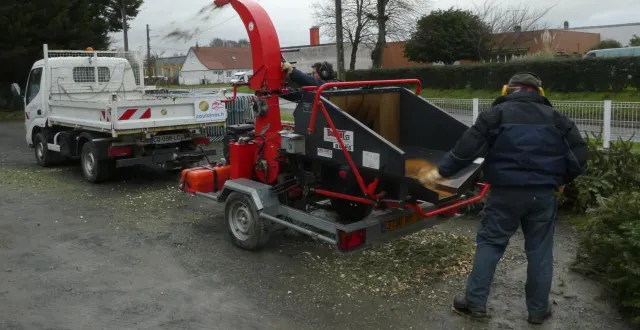 photo  deux agents alimentent le broyeur en sapin de noël et le broyat arrive dans le plateau du petit camion auquel il est attelé.  &copy;  ouest-france 
