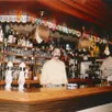 photo  didier benatre derrière son bar du café des vosges, orné des fanions de clubs amateurs du 49. 