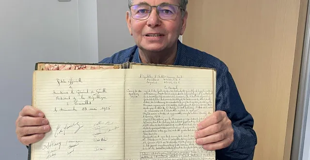 photo  jean-pierre coué devant le registre attestant de la venue du général de gaulle à louailles en 1965. la signature de son grand-père côtoie celle du président d’alors.  &copy;  le maine libre 