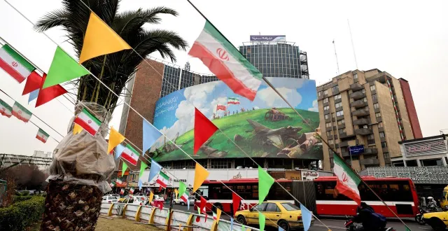 photo  un bus passe devant un grand panneau anti-états-unis à téhéran, le 8 février 2026.  &copy;  atta kenare / afp 