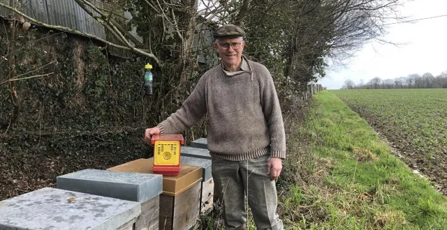 photo  marcel hamard près des ruches de son fils, guillaume, un piège à frelons asiatiques à la main.  &copy;  ouest-france 