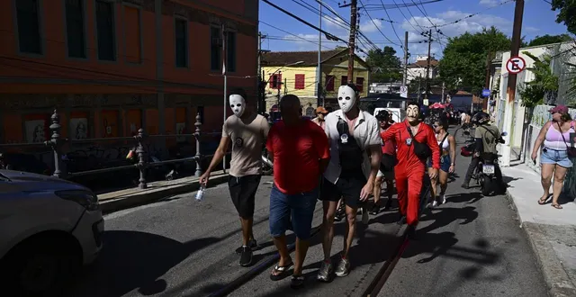 photo  des officiers de police escortent un homme et une femme soupçonnés d’avoir volé des téléphones pendant le carnaval de rio au brésil, le 13 février 2026.  &copy;  pablo porciuncula / afp 