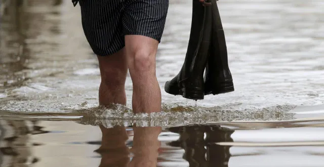 photo  un homme marche dans l’eau avec des bottes dans une main. photo d’illustration.  &copy;  christian hartmann/reuters 