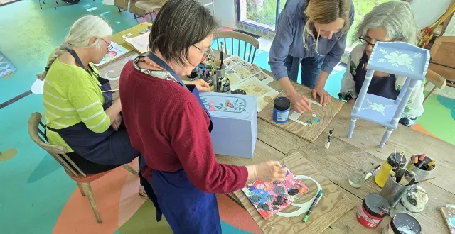 photo  pinceau à la main, stéphanie lelong guide les participantes en leur montrant différentes techniques.  &copy;  nébia séri 