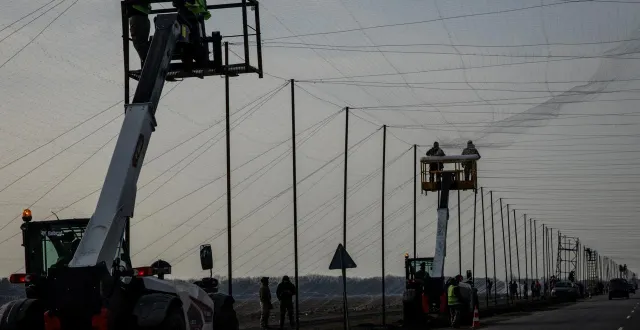 photo  des travailleurs installent des filets antidrones le long d’une route, le 2 mars 2026 à droujkivka, dans l’est de l’ukraine.  &copy;  chris mcgrath / getty images via afp 