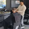 photo enzo boodhoo, manager du salon krys barber de longué-jumelles, en pleine activité avec son client.