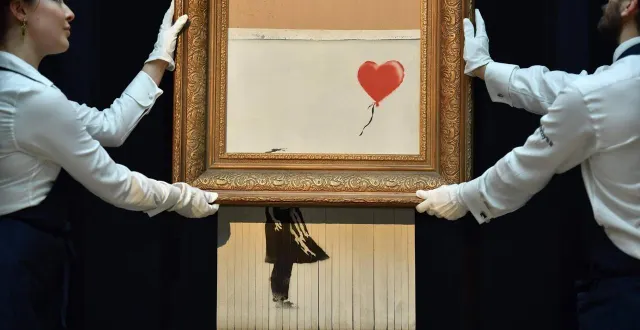 photo  londres, octobre 2021. « la fille au ballon rouge » de banksy, partiellement autodétruite par un mécanisme secret sitôt le marteau du commissaire-priseur abattu pour 1,20 m€ avait atteint le montant record de 18,6 millions de livres trois ans plus tard lors d’une vente chez sotheby’s  &copy;  tolga akmen / afp 