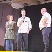 photo manon et joaquim, restaurateurs des 4 saisons, applaudis sur scène par le président du comité des fêtes et les convives.