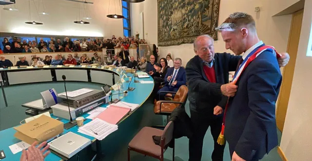 photo  jean-claude barlemont remet à romain lemoigne son écharpe de maire, devant une salle plus que comble.  &copy;  le maine libre - louis gohin 
