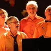 photo les 34 choristes et cinq musiciens de clé de fa sont toujours vêtus de chemises orange lors de leurs représentations. ils proposent un concert avec la chorale cigal’mélodie.